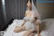 A woman in a wedding dress sitting on a bed.