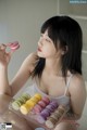 A woman sitting on the floor holding a tray of macarons.