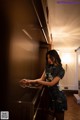 A woman in a short dress leaning against a piano.