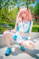 A woman with pink hair sitting on a concrete ledge.