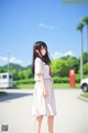 A woman in a white dress standing on a street.