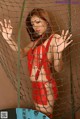 A woman in a red bikini posing behind a net.