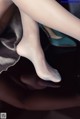 A close up of a woman's legs in white stockings and high heels.