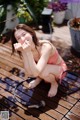 A woman sitting on a wooden deck with a hose.