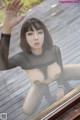 A woman in a black bodysuit posing on a wooden deck.