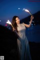 A woman in a long dress holding a sparkler.