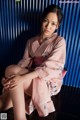 A woman in a pink kimono sitting on the floor.