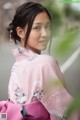 A woman in a pink kimono is posing for a picture.