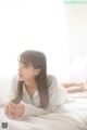 A woman laying on a bed in a white shirt.