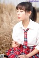 A young woman in a school uniform holding a stick of grass.