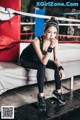 A woman sitting on a bench in a boxing ring.