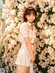 A woman standing in front of a wall of flowers.