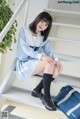 A woman in a school uniform sitting on a set of stairs.