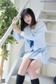 A woman in a school uniform is sitting on the stairs.