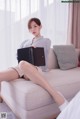 a woman sitting on top of a couch holding a laptop