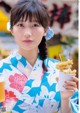 A woman in a kimono holding a cup of food.