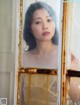 A woman looking out of a window in a white dress.