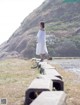 A woman in a white dress standing on a concrete walkway.