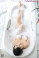 A woman laying in a bathtub covered in foam.