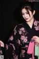 A woman wearing a black kimono with pink flowers on it.