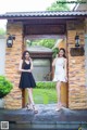 Two women standing in front of a stone building.