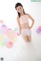 A young woman posing in front of a bunch of balloons.