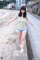 A woman standing on the side of a road next to a beach.