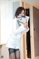 A woman in a white jacket and black stockings holding a magazine.