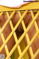 A close up of a person's penis behind a yellow fence.