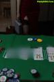 A woman standing behind a poker table with cards and chips.