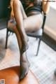 A woman sitting on a chair with her legs crossed.