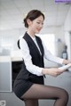 A woman in a black skirt and white shirt is holding a tablet.