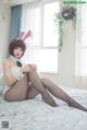 A woman in a bunny costume sitting on a bed.