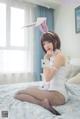 A woman in a bunny costume sitting on a bed.