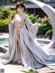 A woman in a white kimono standing next to a pool.