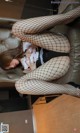 A woman in fishnet stockings is sitting on a couch.