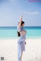 A woman in a blue dress standing on a beach.