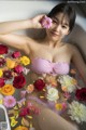 A woman in a bathtub with flowers floating around her.