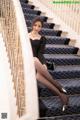 A woman in a black dress sitting on a set of stairs.