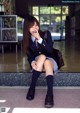 A woman in a school uniform sitting on a bench.