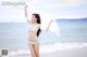 A woman in a white bikini standing on a beach.