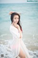 A woman in a white dress standing on the beach.