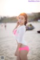 A woman in a pink bikini standing on a beach.