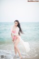 A woman in a pink bikini standing in the ocean.