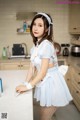 A woman in a blue dress is cleaning a kitchen counter.