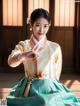 A woman in a hanbok is holding a bouquet of flowers.