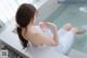 A woman in a white dress sitting in a bathtub.