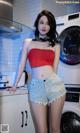 A woman standing in front of a washing machine in a kitchen.