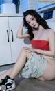 A woman sitting on the floor in a kitchen next to a washing machine.